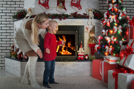 节日快乐可爱的小孩和妈妈在圣诞树下发现了许多礼物。