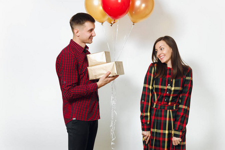 美丽的年轻幸福的微笑情侣在爱。妇女和人拿着礼物和红色的金黄礼物箱子, 黄色气球, 庆祝生日, 在白色背景隔绝了。假日, 党概念