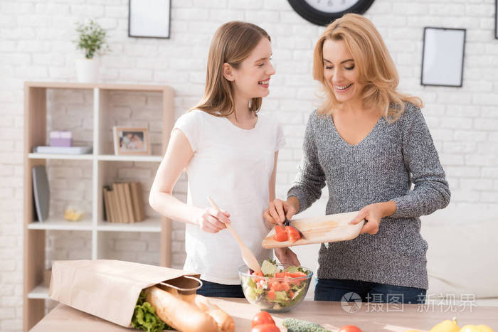 妈妈和女儿一起在厨房做饭. 他们用蔬菜做饭. 他们心情很好.