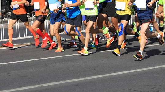 马拉松赛跑运动员的腿在城市道路上奔跑