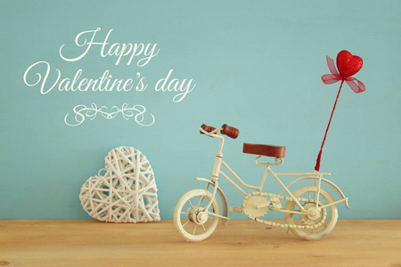 情人节浪漫背景与白色复古自行车玩具和闪闪发光的红色的心在它的木桌上