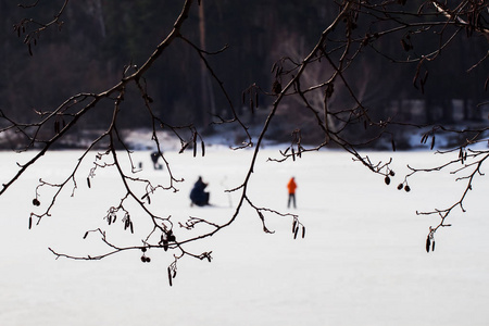 冬季垂钓。河流, 湖附近的森林在冰。模糊的形象钓鱼者, 渔民通过树枝, 最喜欢的男人休闲时间, 家庭, 孩子