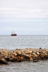 海洋景观，地平线上有一艘娱乐船，前景是一个石墩