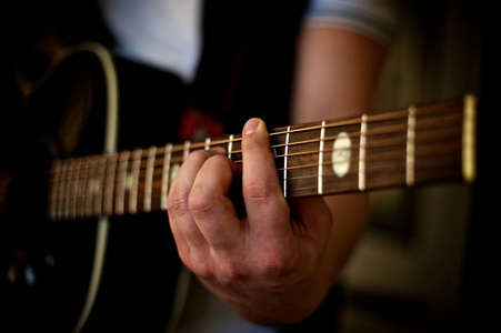 s hand playing a chord on an acoustic guitar.