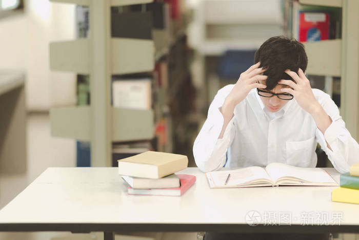 照片 年轻的学生在图书馆努力学习.