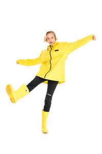 年轻女子穿着时尚的黄色雨衣和雨靴，被隔离在白色上