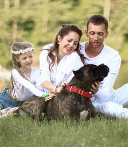 幸福的家庭带宠物狗在阳光明媚的夏日野餐。孕甾
