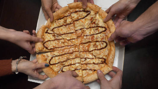 近距离的人手拿切片的比萨饼。特写的人手拿切片的辣香肠比萨饼。朋友吃比萨饼顶部视图