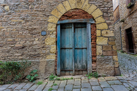 苍白的蓝色和破旧的门在一个小镇的石墙 Fr