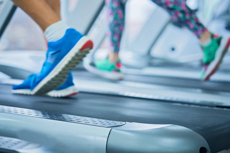 穿着运动鞋在健身房跑步机上跑步的女性肌肉脚
