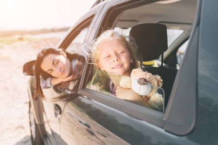 愉快的家庭在他们的汽车旅途中。爸爸妈妈和女儿在海边或海边或河边旅行。汽车夏季乘车