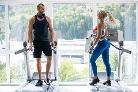 体育健身生活方式技术和人们的概念，近距离的女人和男人的腿在跑步机上行走在健身房。