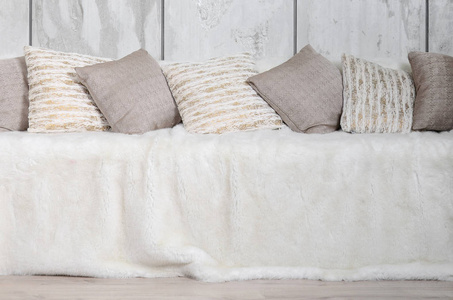 许多枕头躺在沙发上，沙发上覆盖着一层厚厚的毛绒面纱，背景是大理石墙