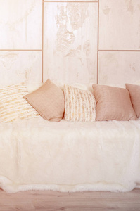 许多枕头躺在沙发上，沙发上覆盖着一层厚厚的毛绒面纱，背景是大理石墙