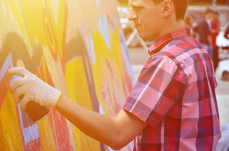 一位年轻的红发涂鸦艺术家在墙上画了一幅新的涂鸦。画墙特写涂鸦的过程照片..街头艺术和非法破坏的概念