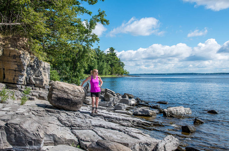在山普兰湖的岩石海岸上一个女人走着，向外望着湖面