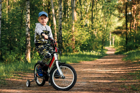 清晨在森林里骑自行车的孩子。 男孩骑自行车户外头盔