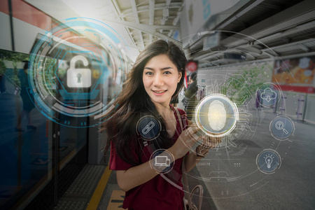 亚洲女性乘客使用技术平板电脑进行指纹扫描，以支持安全访问，并在空中列车轨道或地铁上进行生物识别