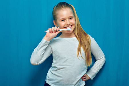 蓝墙背景的小女孩用牙刷刷牙
