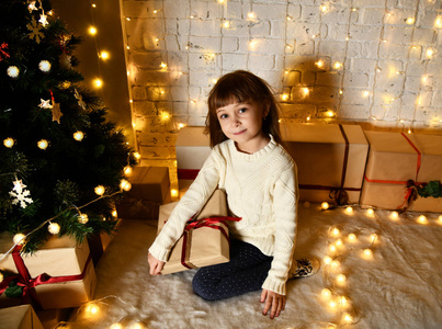 亚洲儿童女婴的孩子坐在装饰黄金圣诞树的黄金拼接礼品礼物