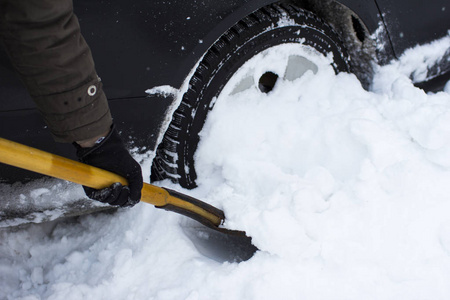 一个人用雪铲清洗汽车