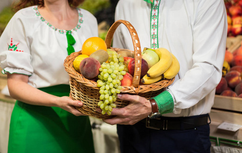 妇女和男子手中捧着一篮子水果在市场上收获