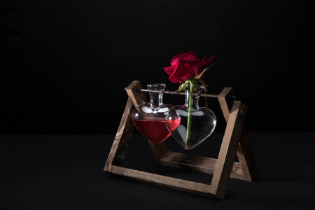 红玫瑰是心形花瓶和花瓶，与爱情灵丹妙药隔离在黑色上