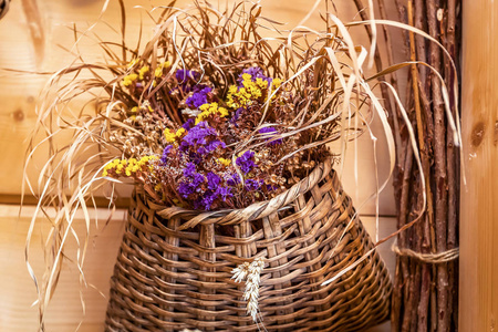 木墙背景上柳条篮子里的花。 柳条篮子里的花