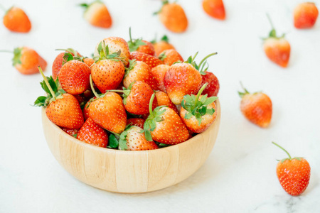 白色石头背景的木碗中的草莓水果