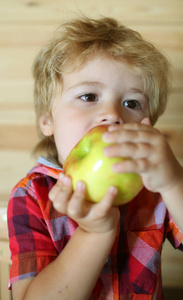孩子或金发碧眼的快乐男孩吃苹果
