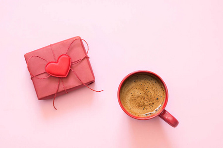 一杯咖啡和礼物与爱在粉彩粉红色。顶部视图。情人卡