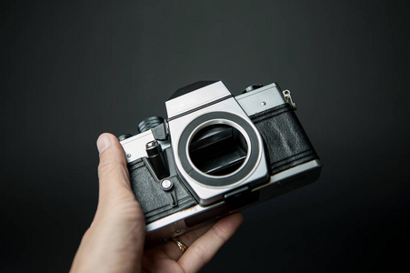 s hand holding a old camera on a black background