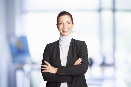 微笑的执行财务顾问女商人站在办公室交叉双臂。
