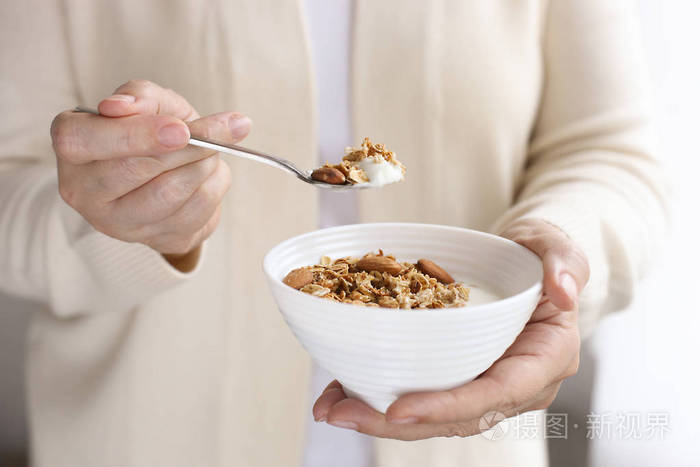 女性手捧着健康的素食超级, 配以腰果,杏仁,榛子.清晨的灯光, 关