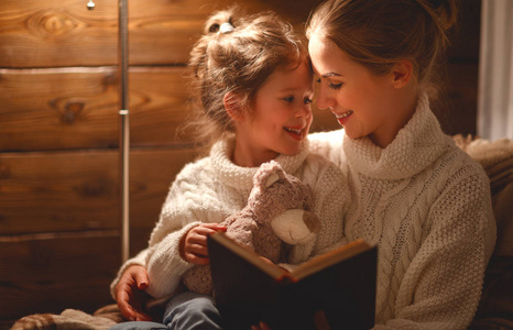 愉快的家庭母亲和孩子女儿读一本书在冬天 e