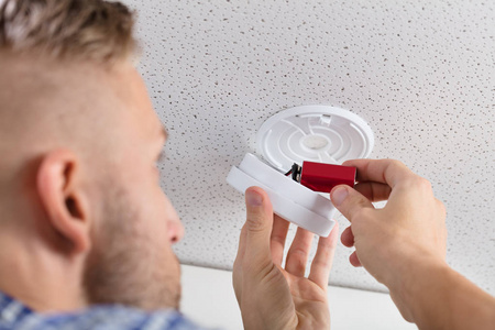 s Hand Inserting Battery In Smoke Detector