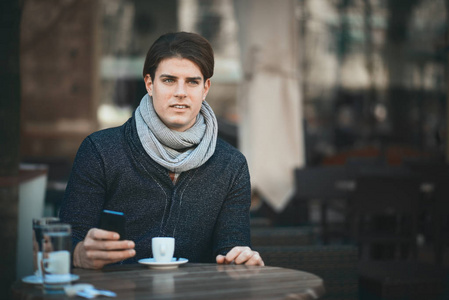 男人坐在咖啡馆里用智能手机喝咖啡。