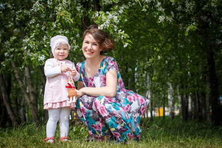 母亲和女儿在公园和苹果的树与白花玩得开心
