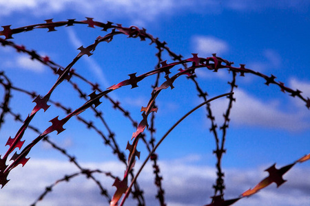监狱.有刺铁丝网有刺铁丝网在蓝天背景与白云。电线爆炸军事冲突。