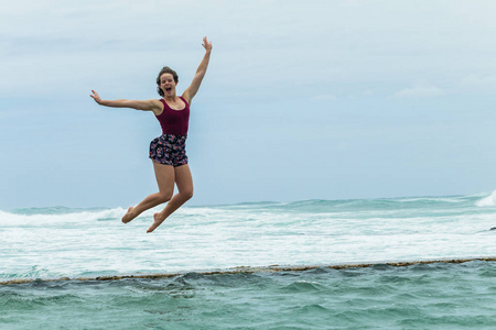 女孩跳跃的海滩假日水池海洋