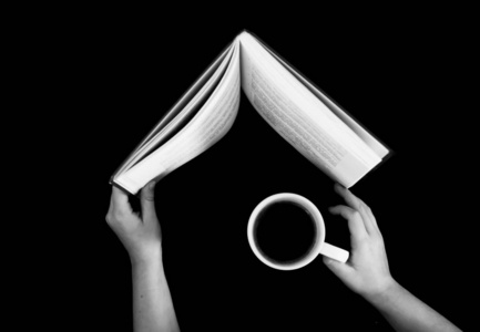 blackand白色的手拿着一本书和一杯咖啡顶视图