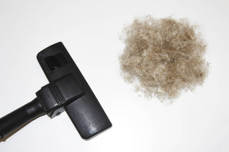 清洁概念。真空吸尘器和白色背景的羊毛球。吸尘器和头发的刷子