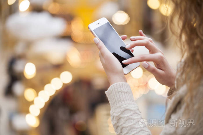 美丽的女性手拿着手机在室内