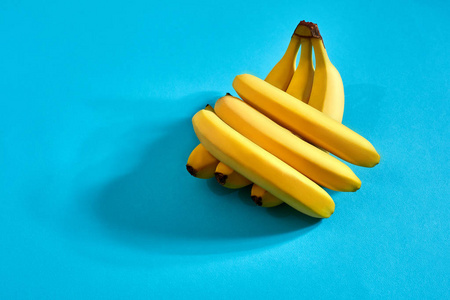 新鲜的香蕉靠近明亮的蓝色背景。平躺。夏日理念