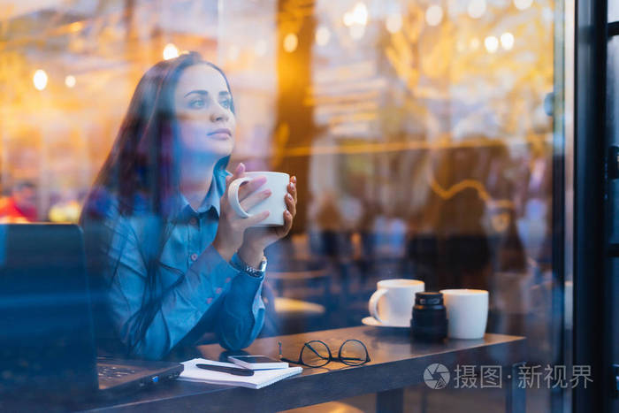 坐在窗户外面喝咖啡的妇女