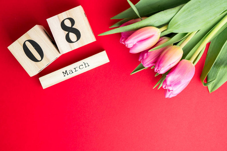 s Day concept. With wooden block calendar and pink tulips on red