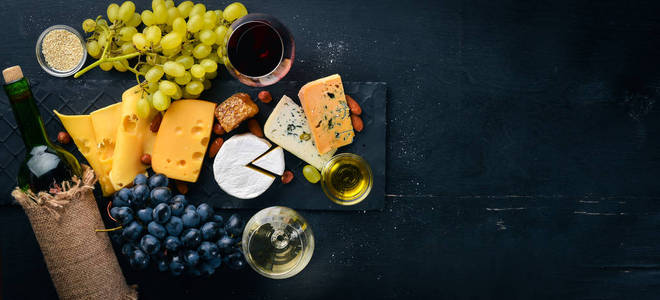各种奶酪，一瓶葡萄酒，蜂蜜，坚果和香料在木桌上。 上面的风景。 免费的文本空间。