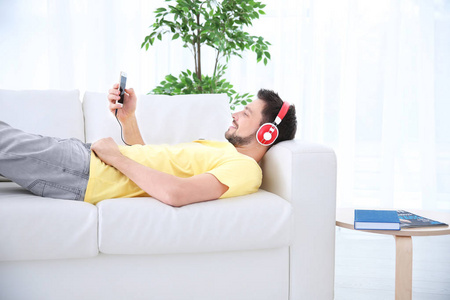 在家休息的年轻人在沙发上听音乐