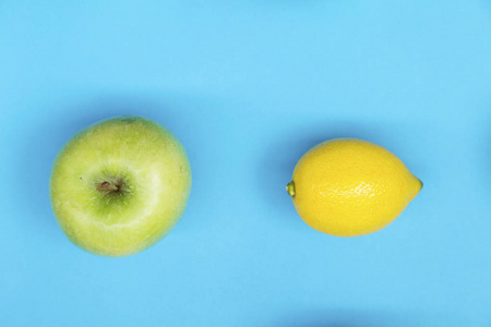 蓝色背景下新鲜柠檬和苹果彩色水果图案的顶部视图。