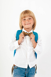学校，孩子，背包。穿着领结的小男孩。快乐微笑的小男孩带着大背包。看着摄像机。学校观念。回到学校